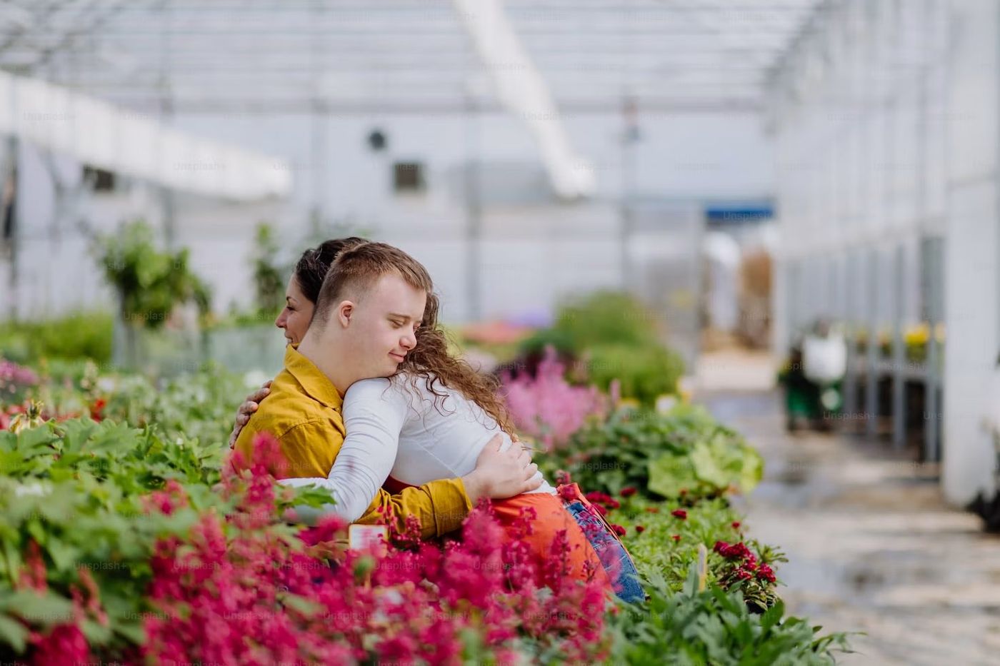 Two participants sharing a warm embrace among flowers at a community nursery